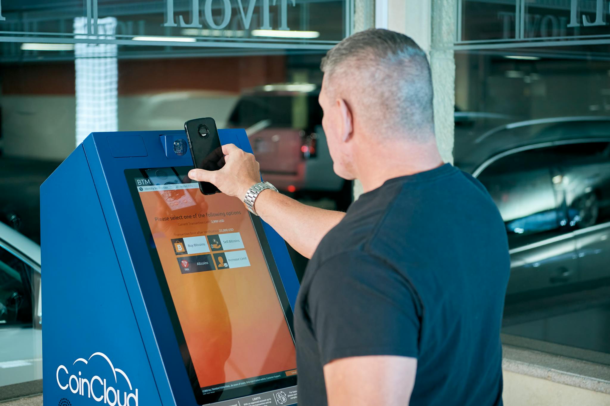 A person using a CoinCloud cryptocurrency ATM in an urban setting, showcasing modern finance technology.