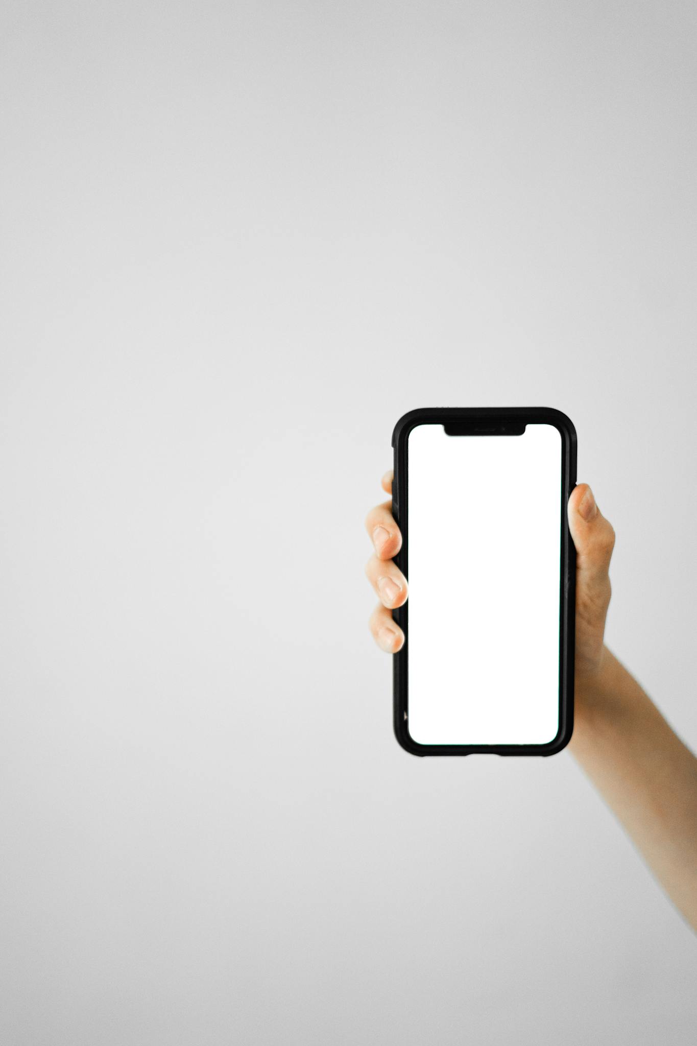 Vertical shot of a hand holding a smartphone with a blank screen, ideal for mockups.